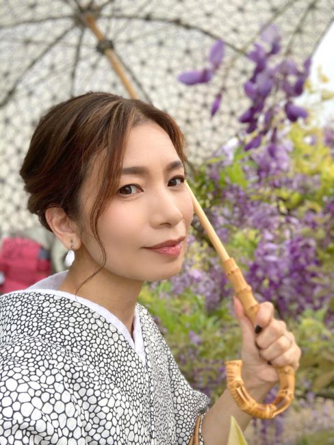 藤花の前で日傘をさして