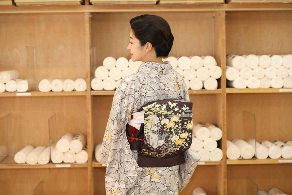 焦茶色の塩瀬地に御所解文様が映えて、後ろ姿も華やかに